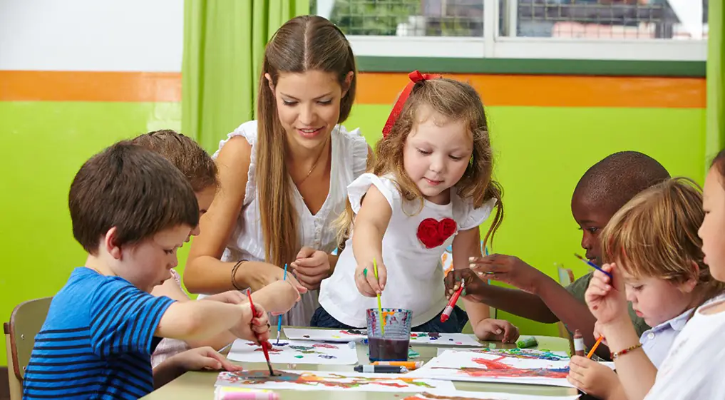 Kinder malen mit Erzieherin im Kindergarten